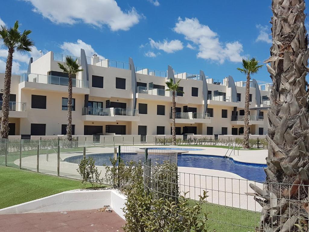 un gran edificio de apartamentos con piscina y palmeras en Playa Elisa Bay MP009, en Torre de la Horadada