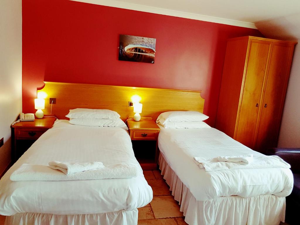 two beds in a hotel room with red walls at King's Head Inn in Llangennith