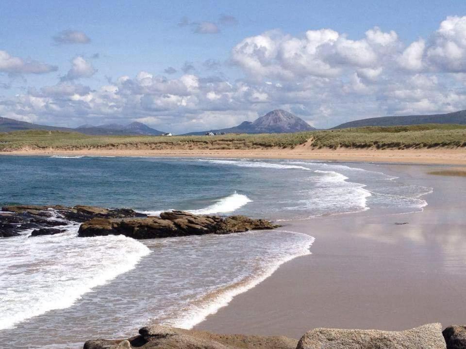 una playa con rocas y el océano y las montañas en Teach Taigh, en Kincasslagh