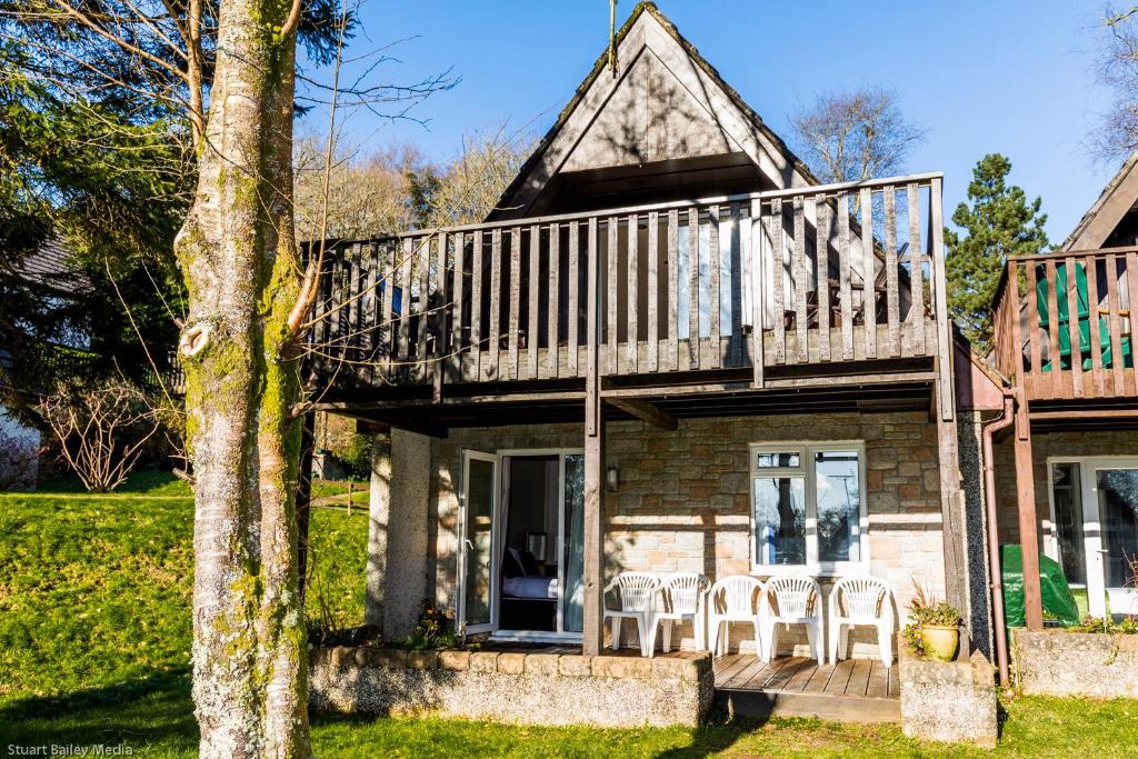 ein Haus mit einer Terrasse und Stühlen auf der Veranda in der Unterkunft Cornwall Countryside Lodges "Reserve Worldwide" Honicombe in Gunnislake