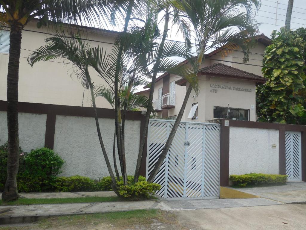 ein Haus mit Palmen vor einem Zaun in der Unterkunft Casa Guarujá - Condomínio in Guarujá