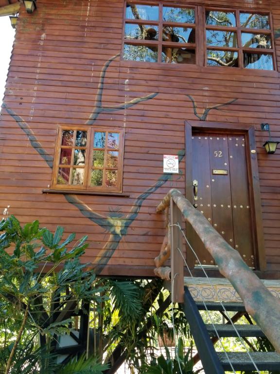 a wooden house with a staircase leading up to the door at Hotel Monte Campana Heredia in Birrí