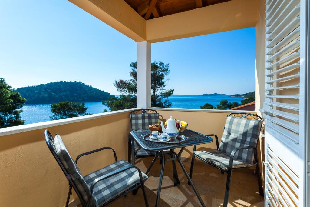 una mesa y sillas en un balcón con vistas al agua en Gold & Silver Apartments en Brna