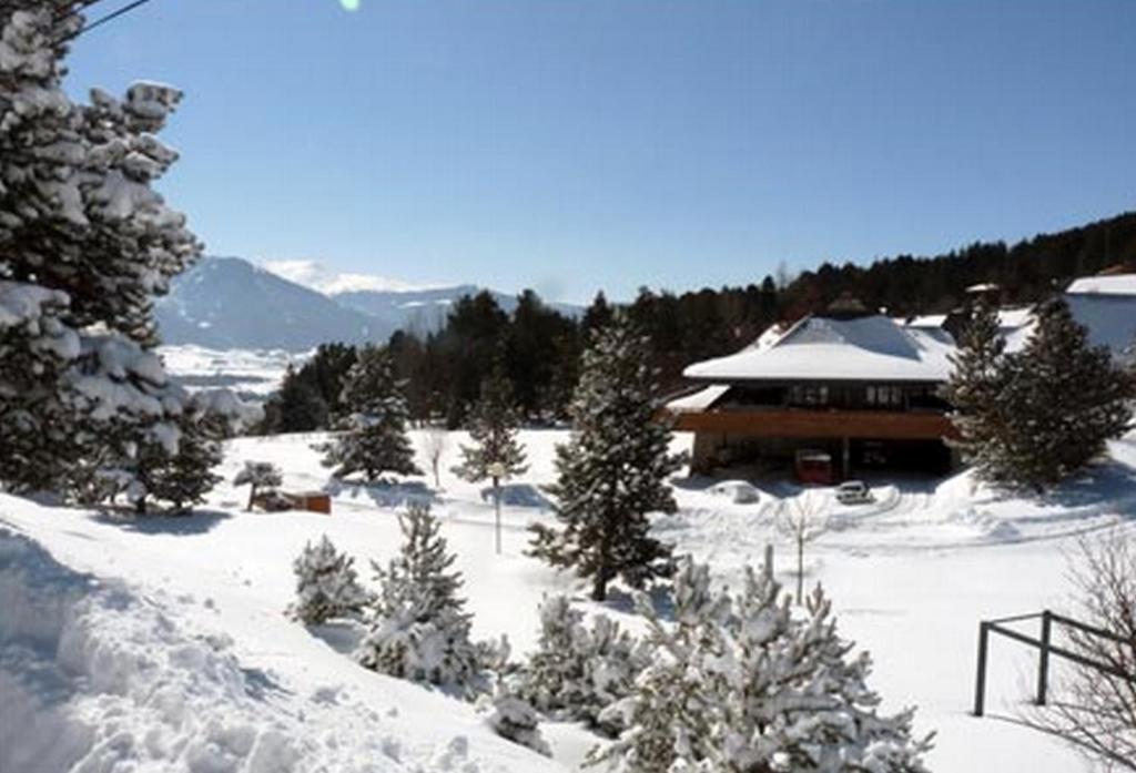 une cour enneigée avec une maison en arrière-plan dans l'établissement Le Chalet du Ticou, à Bolquère-Pyrénées 2000