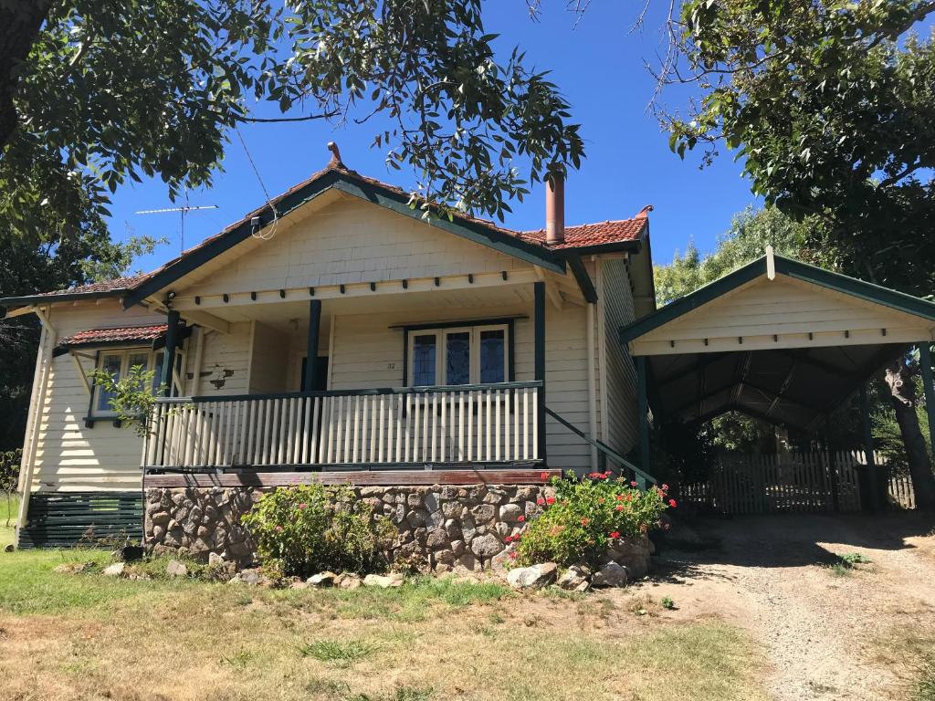 a house with a porch and a fence at Cherry Blossom Cottage - Beechworth-Getaways in Beechworth