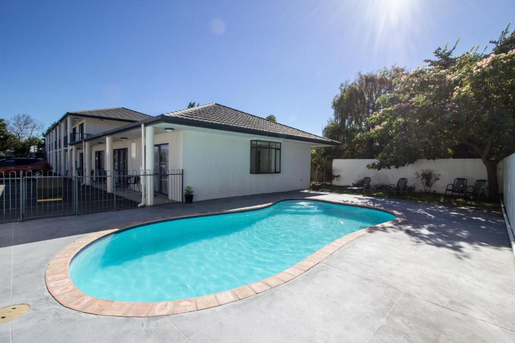 a swimming pool in front of a house at ASURE Phoenix Motor Inn in Blenheim