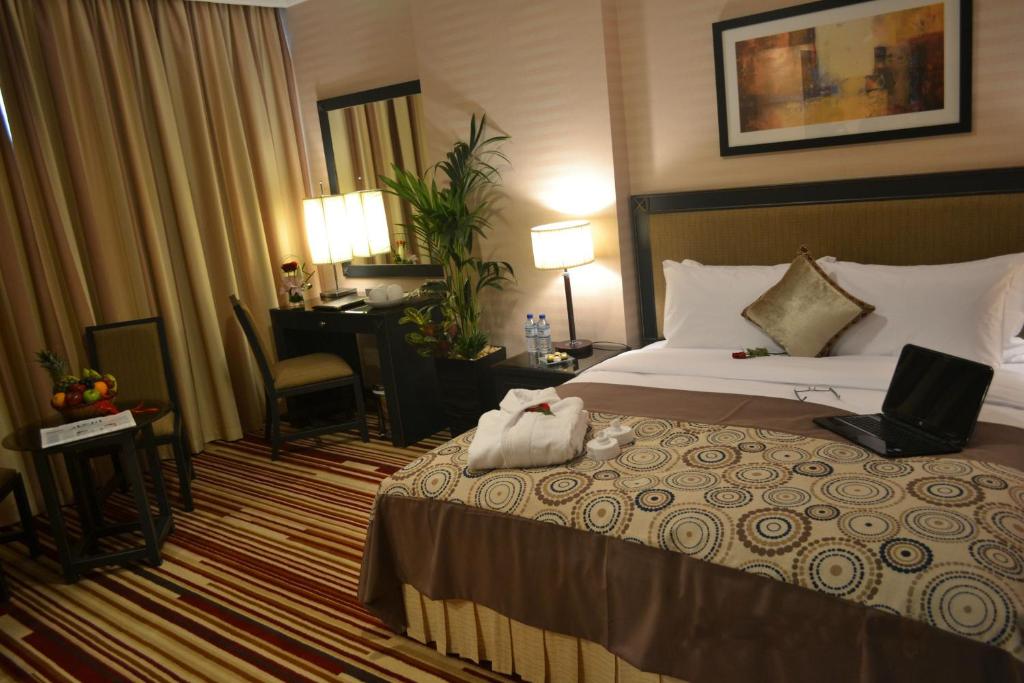 a hotel room with a bed with a laptop on it at Executive Suites Abu Dhabi in Abu Dhabi