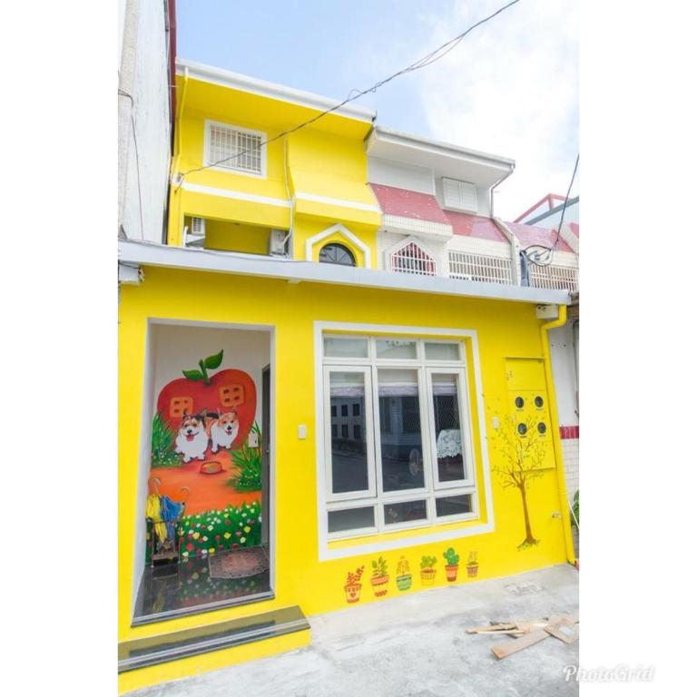 ein gelbes Haus mit einem Gemälde auf der Seite in der Unterkunft Apple House in Hualien