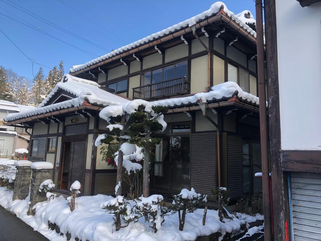 a house is covered in snow with snow at Guesthouse Takayama Hanzansha in Takayama