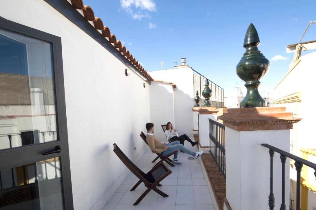 two people sitting on a balcony looking out a window at For You Hostel Sevilla in Seville