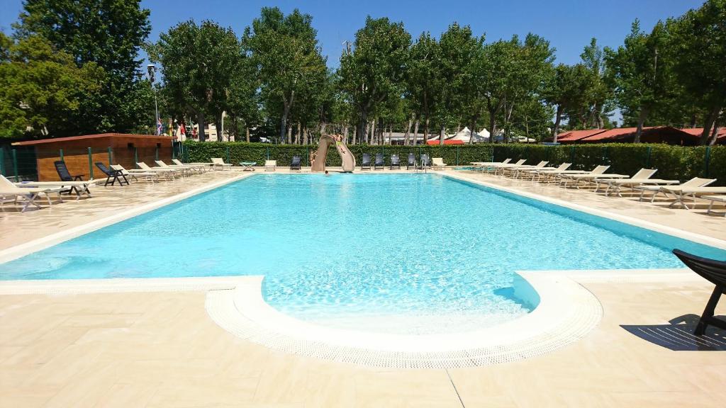 a large swimming pool with lounge chairs at Camping Viareggio in Viareggio