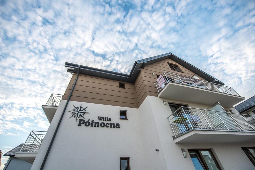 a building with a sign on the side of it at Willa Północna in Karwia