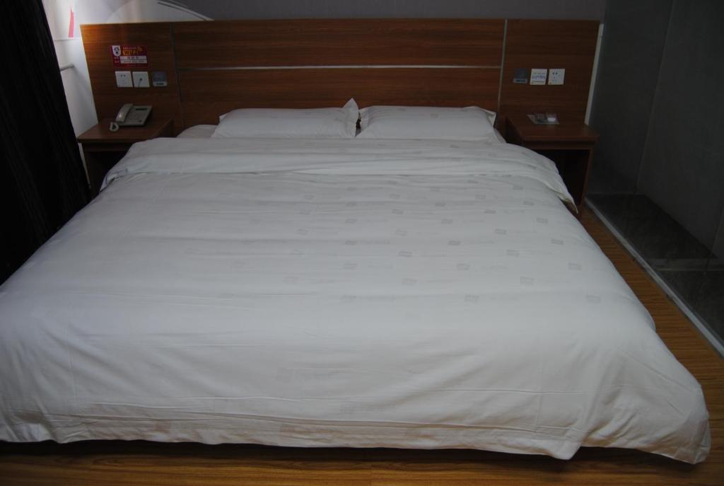 Una cama con sábanas blancas y almohadas. en Thank Inn Chain Hotel Hebei Shijiazhuang High-Tech Area, en Nancun