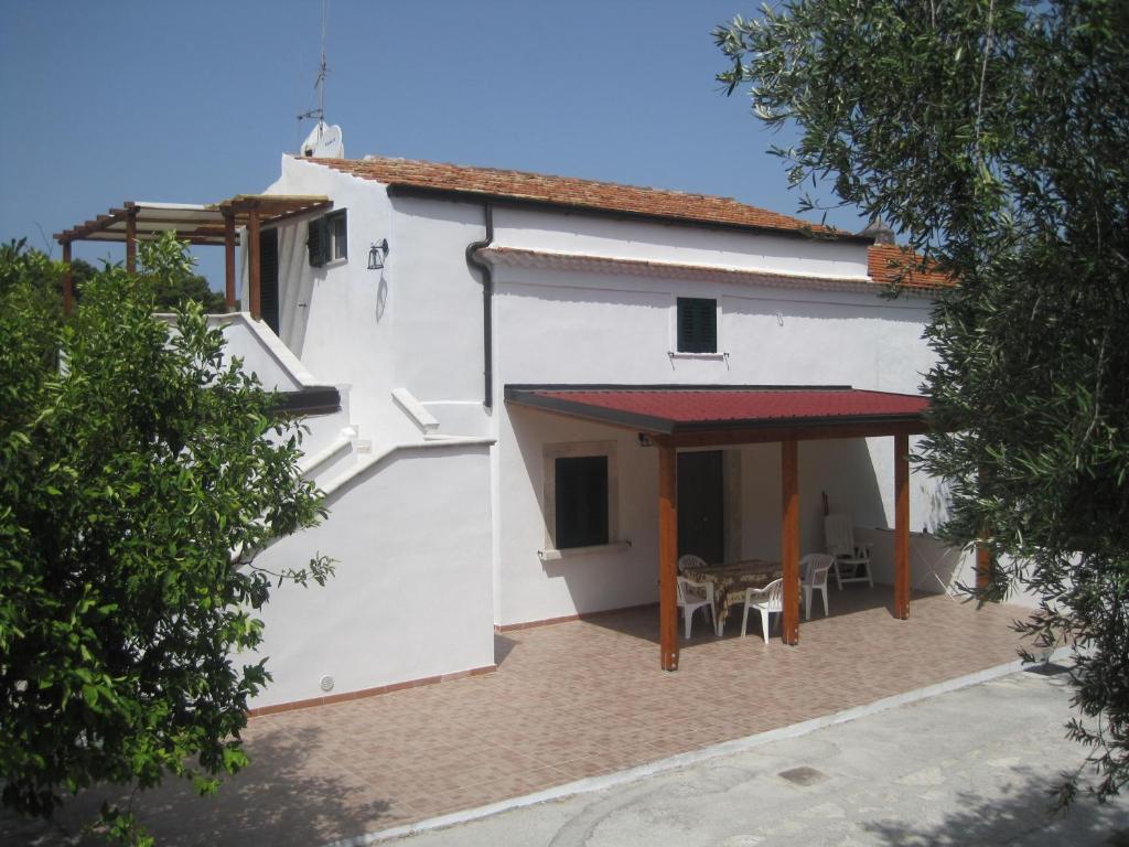 une maison blanche avec un toit rouge et une terrasse dans l'établissement Casa del gelso, à San Menaio
