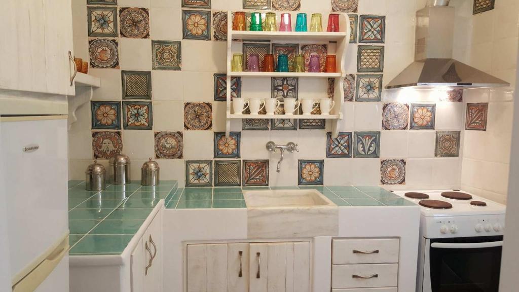 a kitchen with green and white tiles on the wall at Amalthia House in Arkasa
