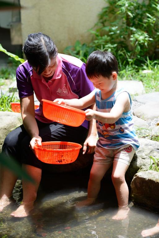 a woman and a young boy playing in the water at Fairy Story Village Farm B&amp;B in Dongshan