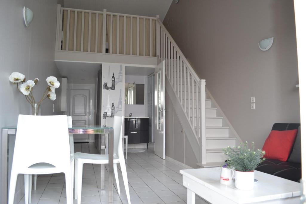 ein Wohnzimmer mit weißen Stühlen und einer Treppe in der Unterkunft Au Pas Du Chateau in Jonzac