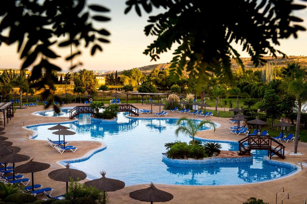 ein großer Pool mit Stühlen und Sonnenschirmen in einem Resort in der Unterkunft Hotel Bonalba Alicante in El Campello