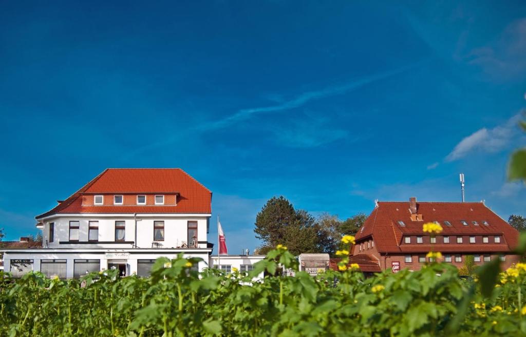 ein weißes Haus mit rotem Dach neben einem Gebäude in der Unterkunft Akzent Hotel Cordes & Restaurant am Rosengarten in Sottorf