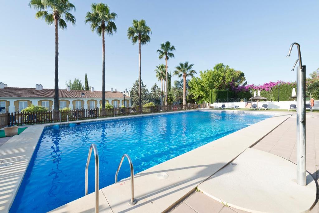 una piscina con palmeras en el fondo en Exe Las Adelfas, en Córdoba