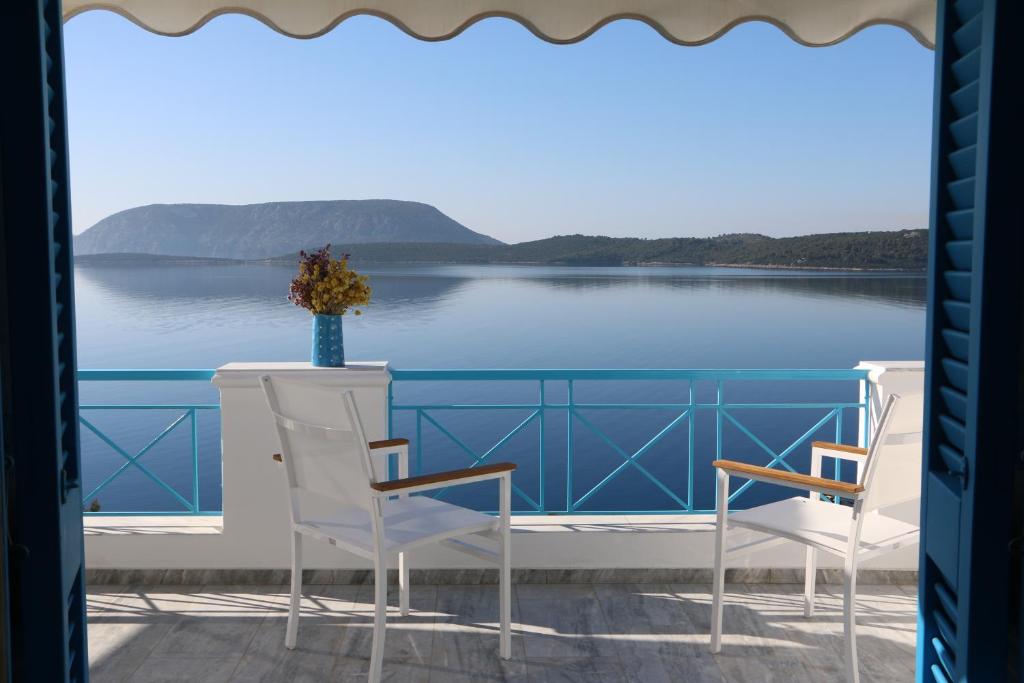 a balcony with two chairs and a view of the water at Grand Bleu Apartments & Villas in Ermioni