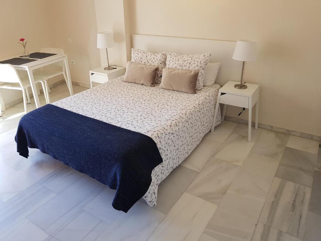 1 dormitorio con 1 cama con manta azul y 2 mesas en Fan Flat Eugenio, en Málaga