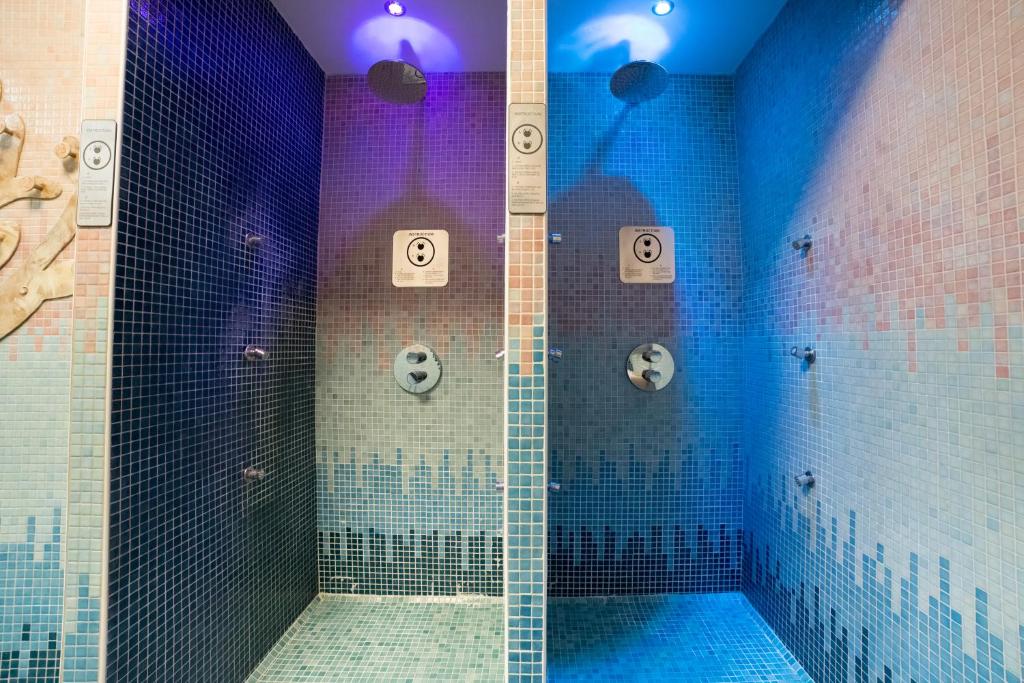 a bathroom with a shower with blue tiles at Unirea Hotel & Spa in Iaşi