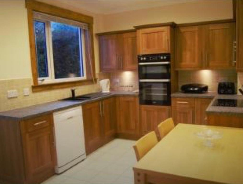 a kitchen with wooden cabinets and a table in it at BalMara in Hopeman