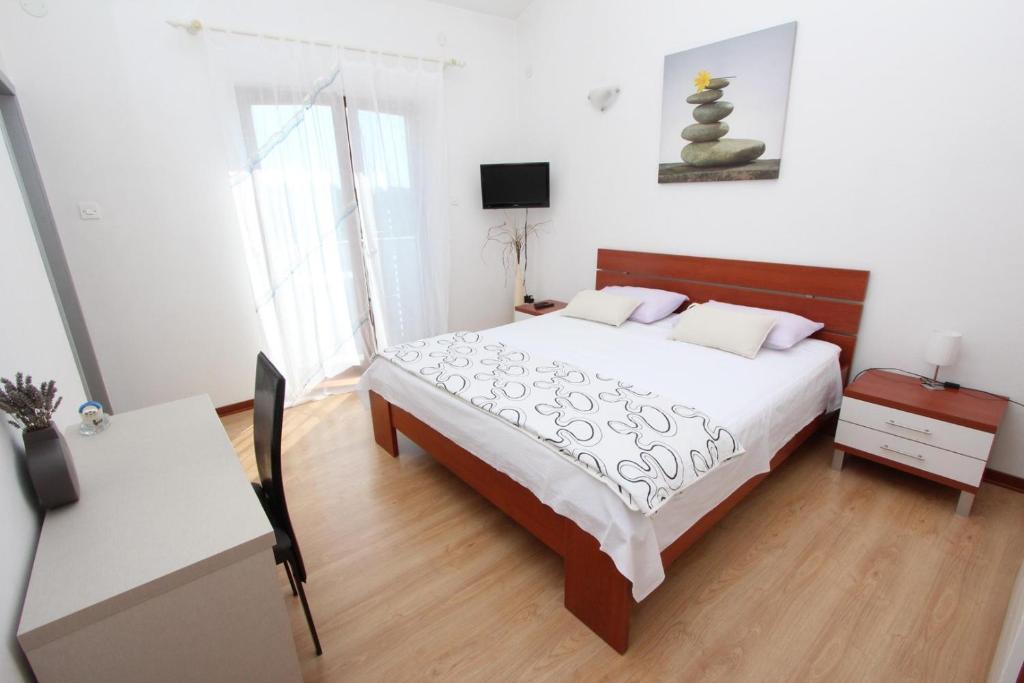 a bedroom with a large bed and a desk and a table at Rooms and Apartment Luana in Rovinj