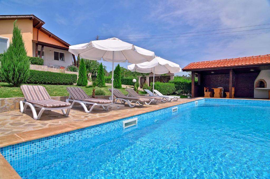 a pool with chairs and umbrellas next to a house at Villa Knox in Bryastovets