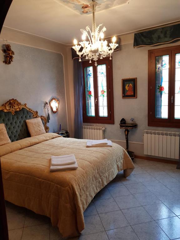 a bedroom with a large bed with a chandelier and windows at Gli Angeli in Venice