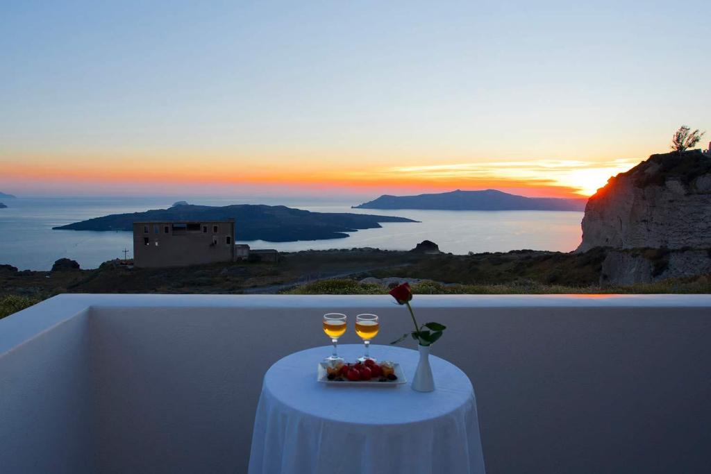 a table with two glasses of wine on a ledge at Nemesis in Fira