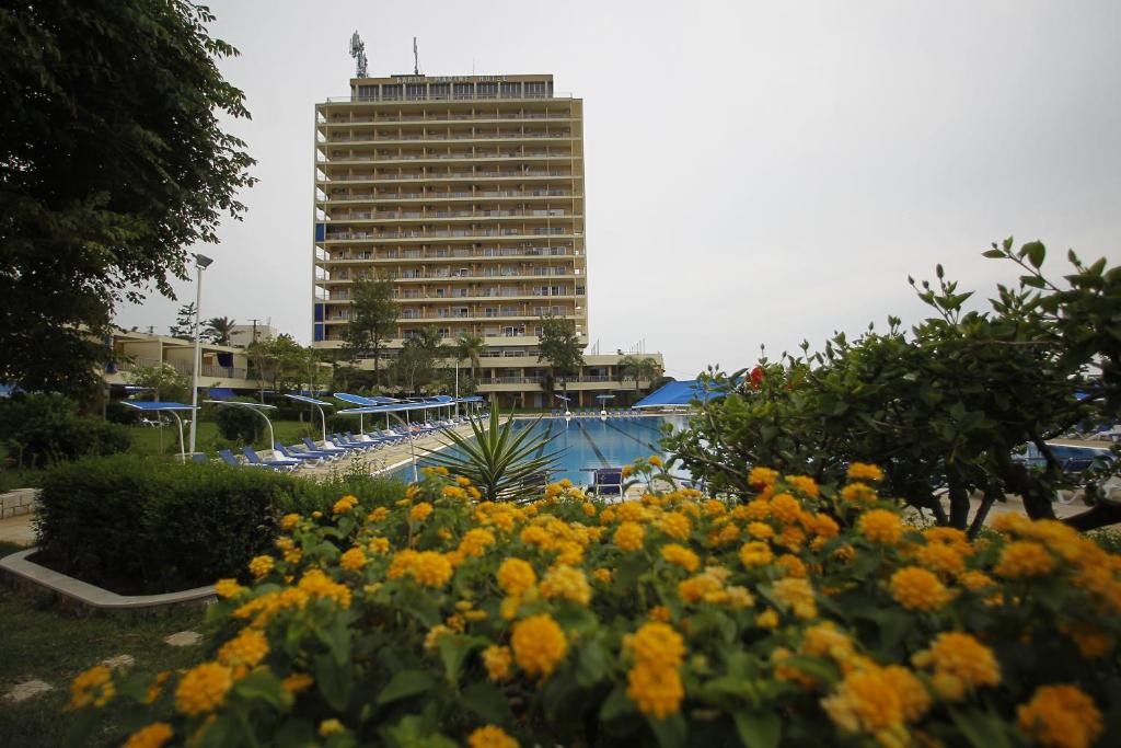 um grande edifício no fundo com flores no primeiro plano em Rabiya Marine Hotel em Ţabarjā