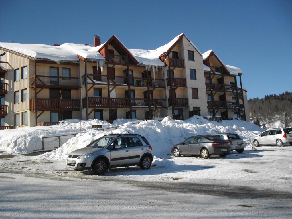 2 voitures garées sur un parking en face d'un immeuble dans l'établissement Les Cretets, aux Rousses