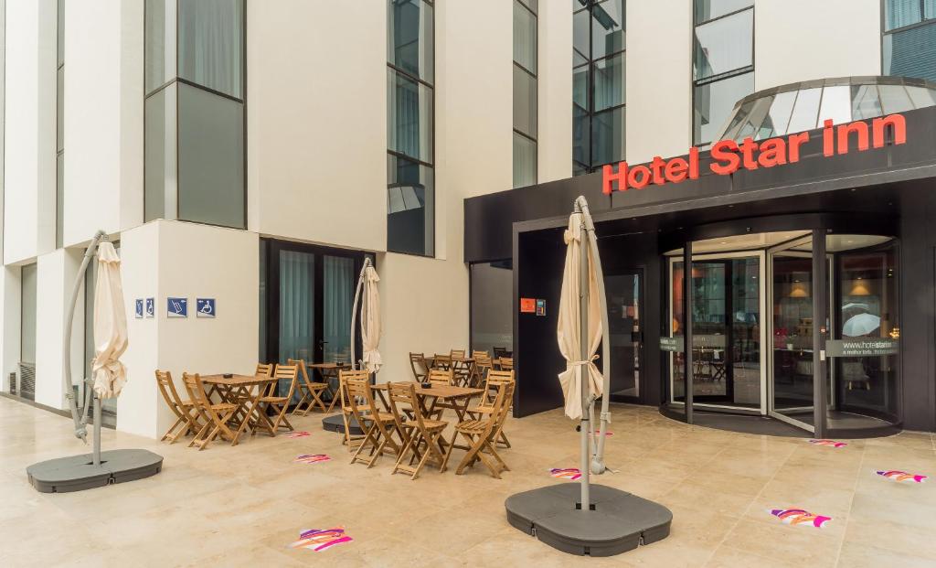 um hotel estrela com mesas, cadeiras e guarda-sóis em Star inn Lisbon Airport em Lisboa