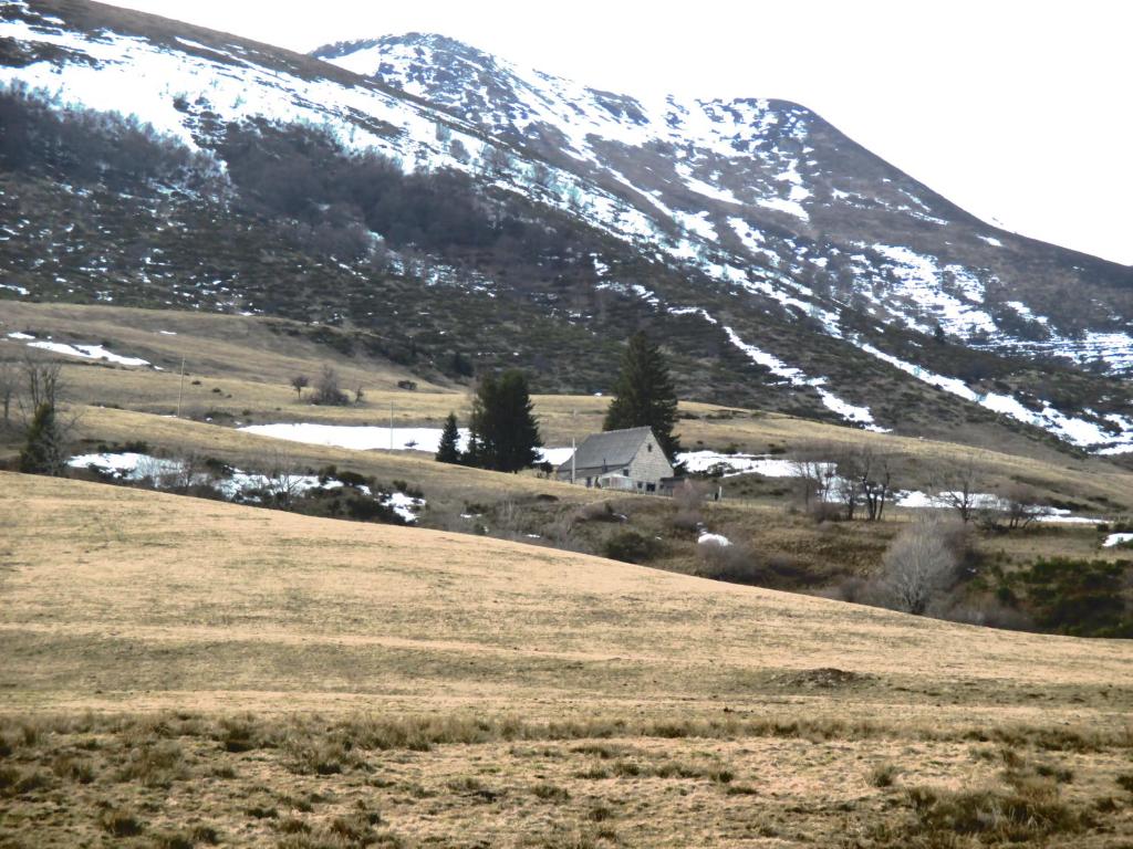 ein Haus auf einem Hügel mit einem schneebedeckten Berg in der Unterkunft le monne (dit la fermette ) in Chambon-sur-Lac