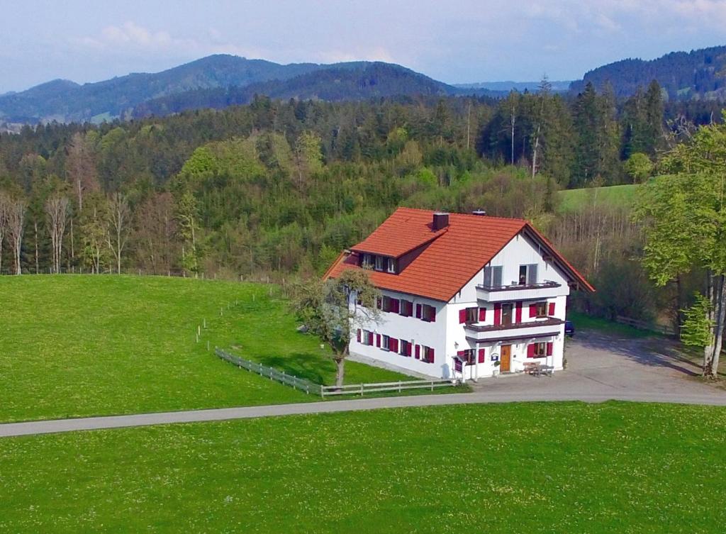 a white house with an orange roof on a green field at Altensberger Hof in Gestratz