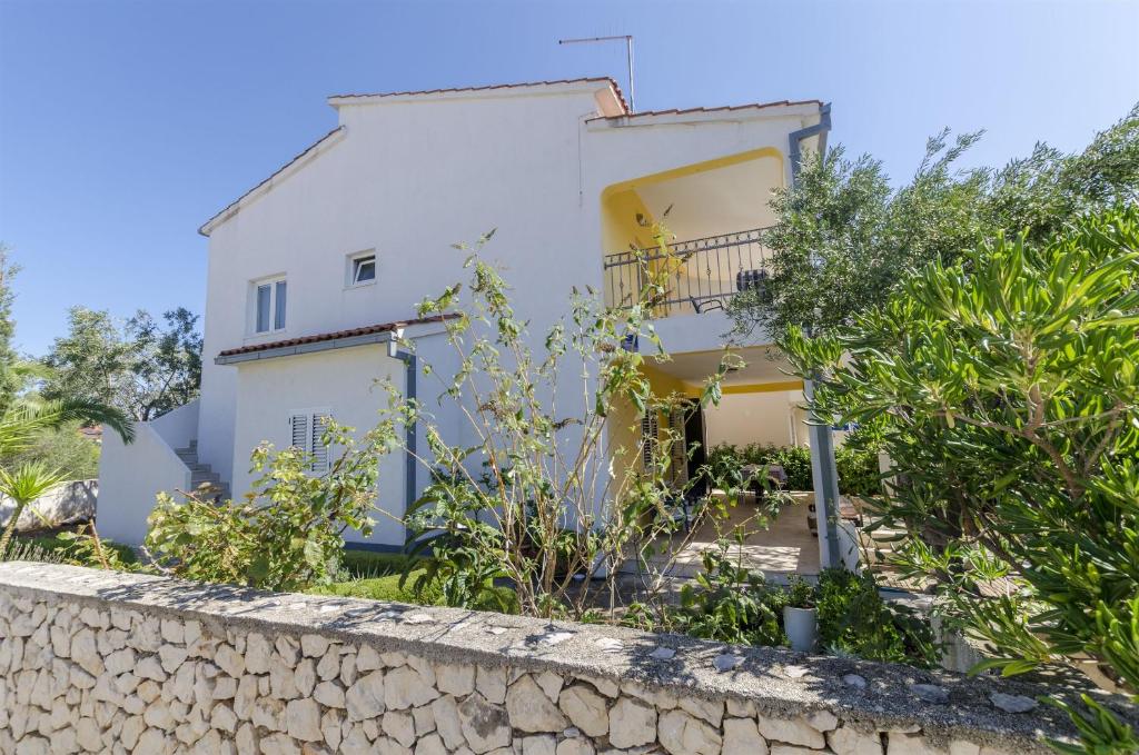 a white house behind a stone wall at Apartments Marija in Ražanj