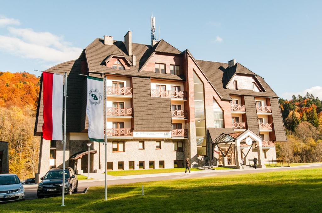 a building with cars parked in front of it at Centrum Promocji Leśnictwa w Mucznem in Lutowiska