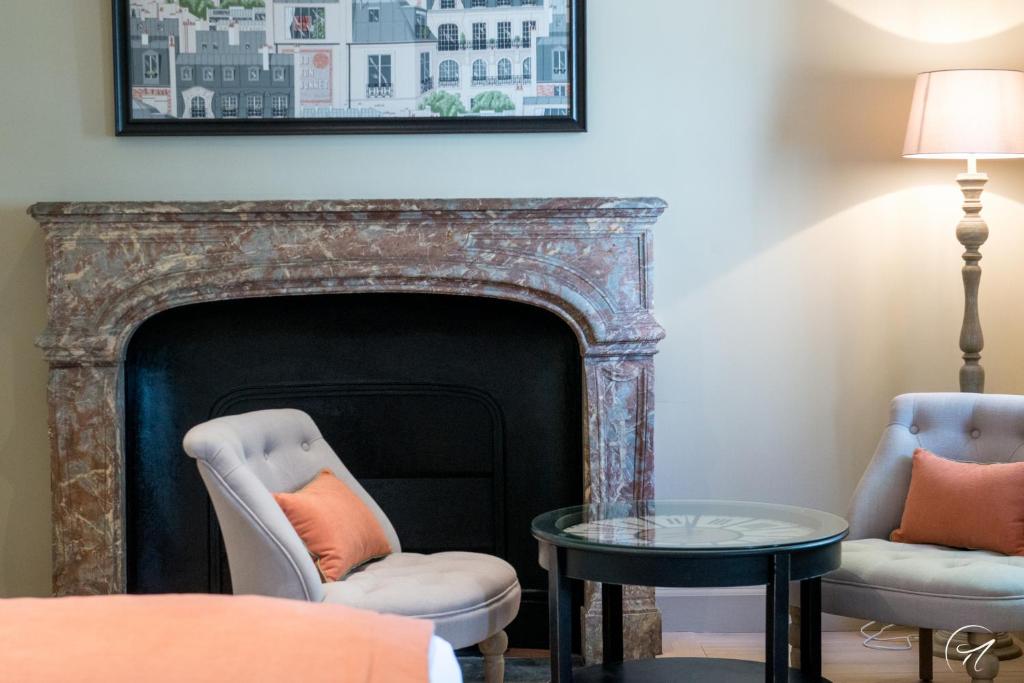 a living room with a fireplace and two chairs and a table at Les Suites du Champagne de Venoge in Épernay
