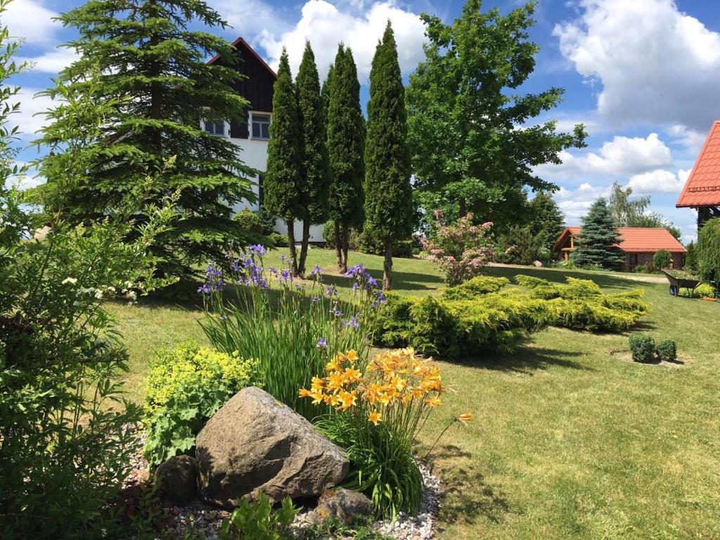 einen Garten mit Blumen und Bäumen und ein Haus in der Unterkunft Haus Masur in Mikołajki