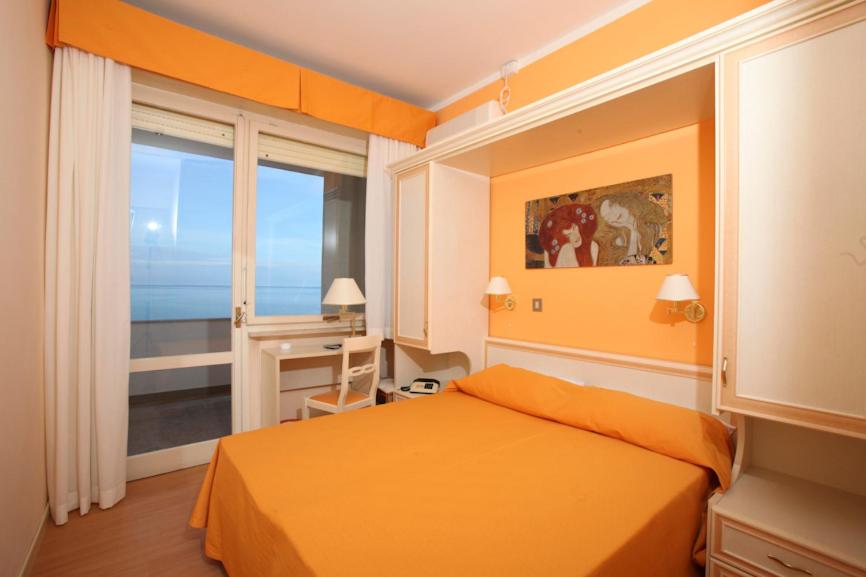 a bedroom with an orange bed and a window at Hotel Hollywood in Senigallia