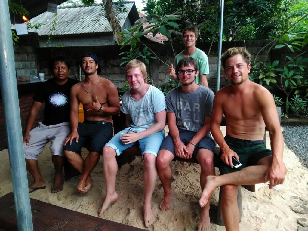 a group of young men sitting on a bench at Made Roejas Homestay in Uluwatu