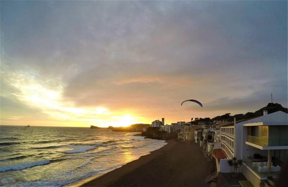 a kite flying over a beach at sunset at Aparthotel Barracuda in Ponta Delgada