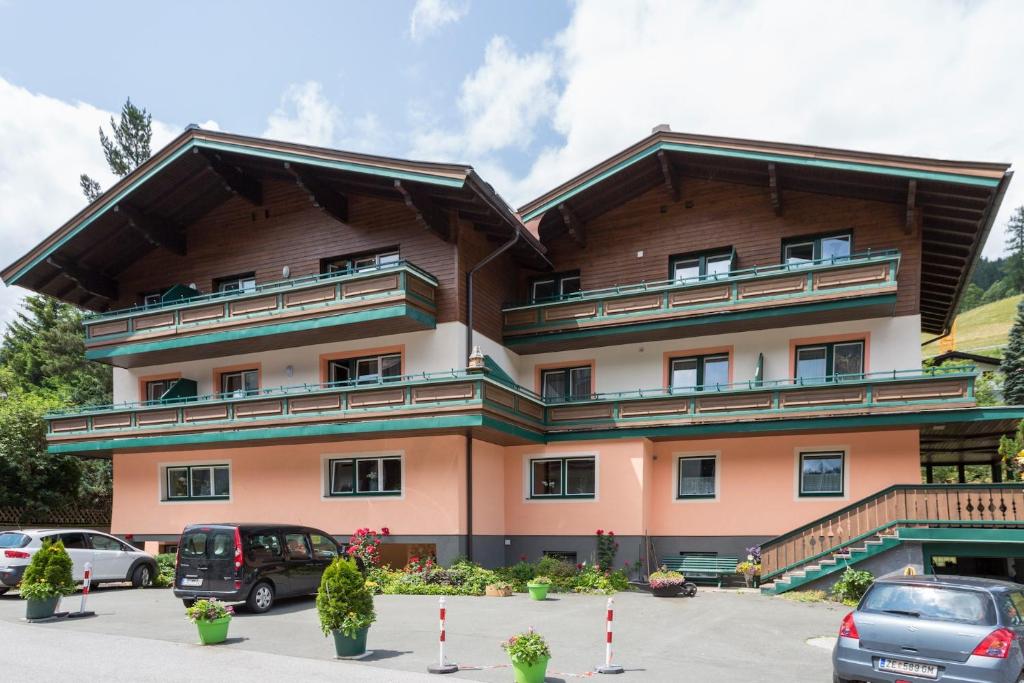 un grand bâtiment avec des voitures garées dans un parking dans l'établissement Pension Ahorn, à Saalbach-Hinterglemm