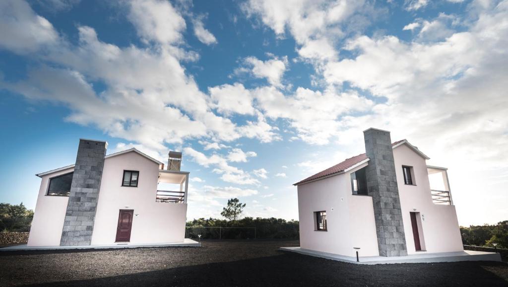 Una casa blanca con dos chimeneas encima. en Vista Montanha, en Madalena