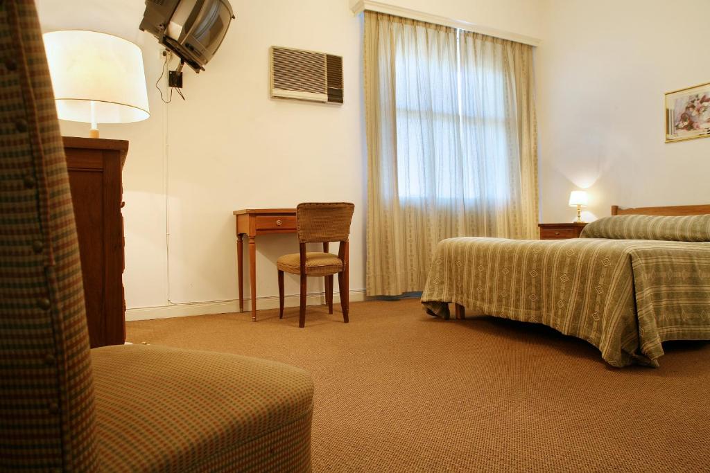um quarto de hotel com duas camas, uma secretária e uma mesa em Constitución Palace Hotel em Buenos Aires