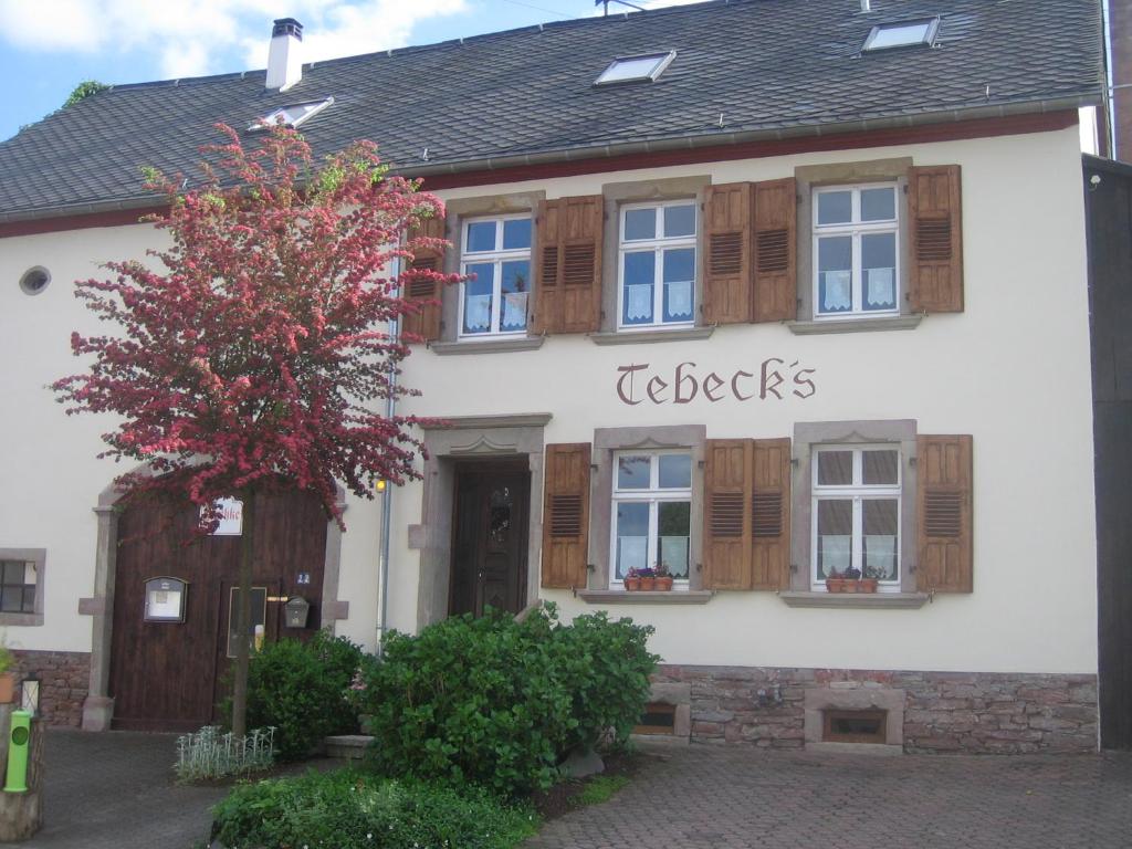 un edificio blanco con persianas de madera en Ferienwohnungen Bistro Tebecks en Wadern