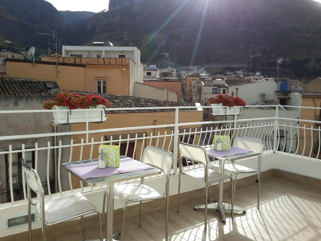 a balcony with two tables and chairs on a roof at White in Castellammare del Golfo