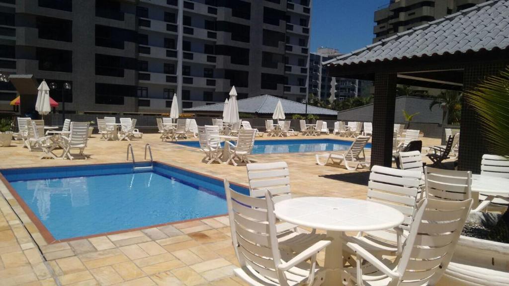 una piscina con sillas, una mesa y una mesa con sillas en Apartamento Atlantico, en Matinhos